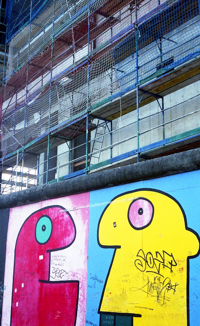 Vibrant graffiti on the Berlin Wall against a backdrop of construction scaffolding.